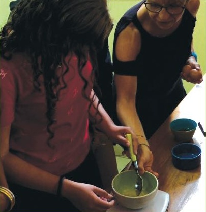 Une adolescente et une encadrante préparent un mélange dans un bol lors d’un atelier cuisine.