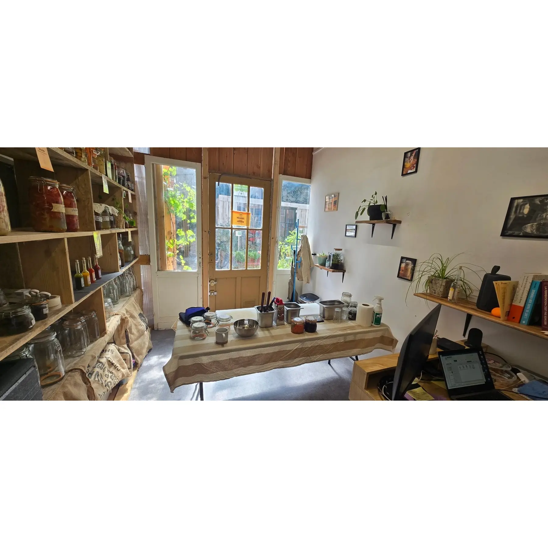 Le même lieu côté boutique : l'entrée vitrée et les étagères garnies de bocaux et de bouteilles de sauces